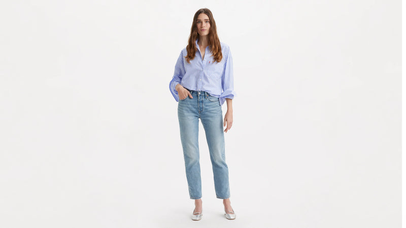 Woman wearing a light blue shirt and jeans on a white background