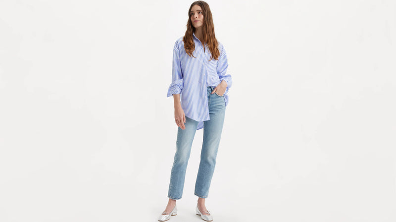 Woman wearing a light blue striped shirt and jeans on a white background