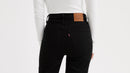 Person wearing black pants with a brown leather patch on a white background