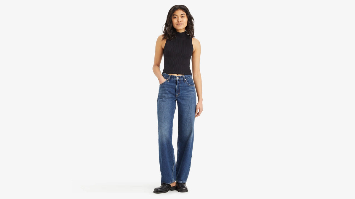 Woman wearing blue jeans and a black top on a white background