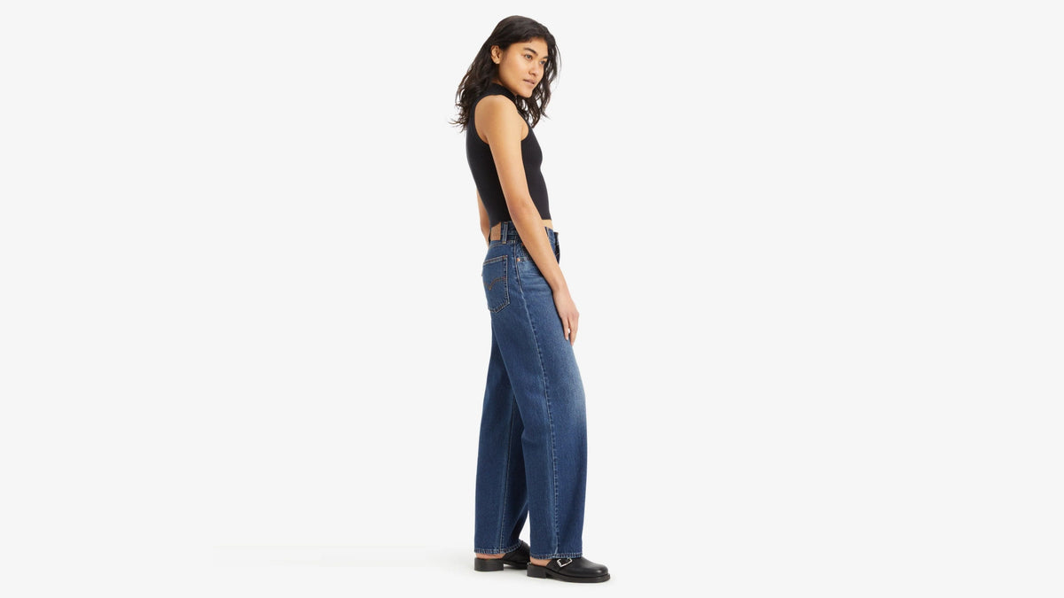 Woman wearing blue jeans and a black top on a white background