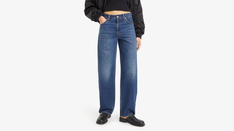 Person wearing blue jeans and a black top on a white background