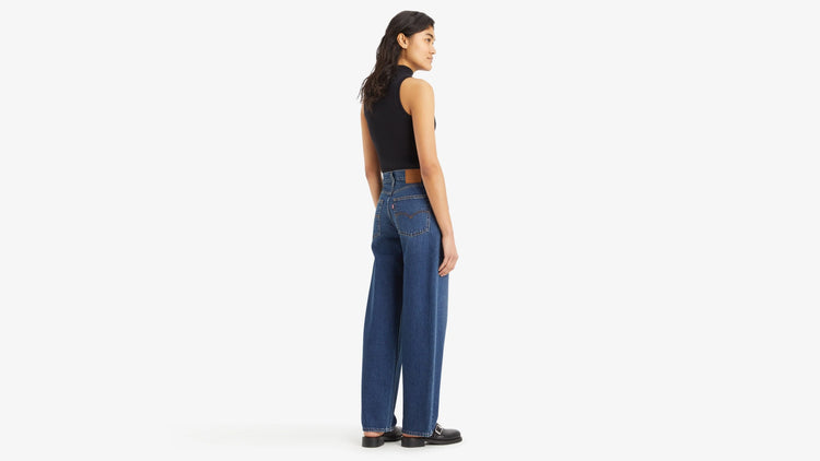 Woman wearing blue jeans and a black top on a white background