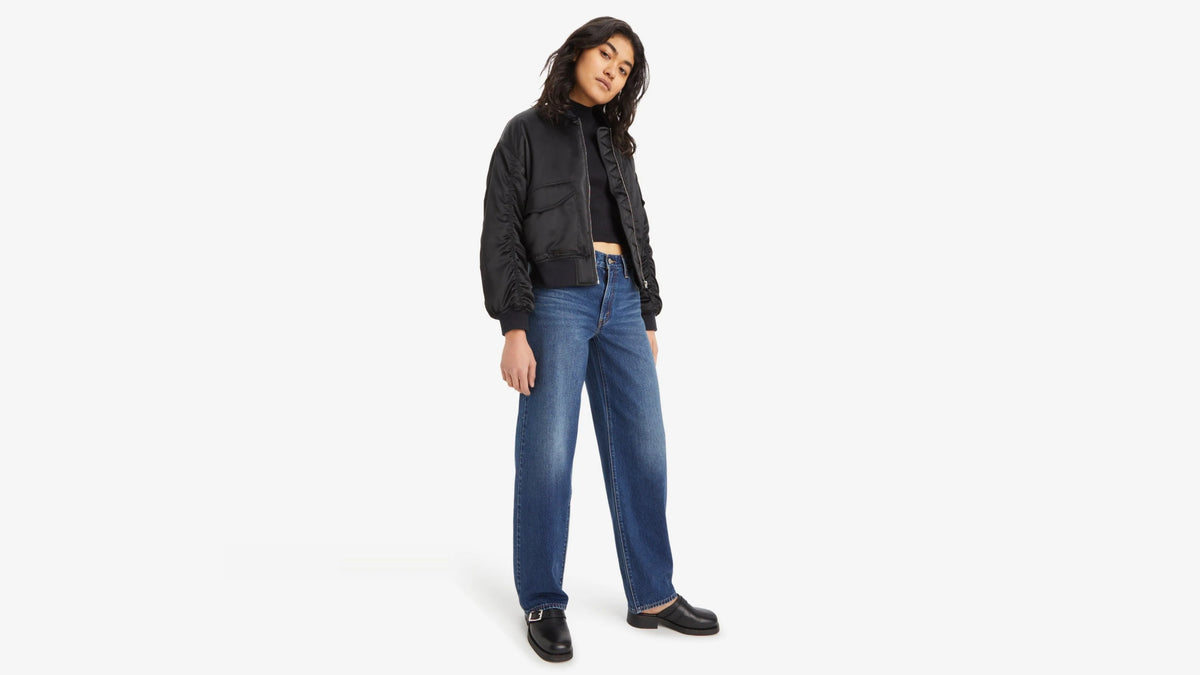 Person wearing a black jacket and blue jeans on a white background