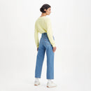 Person wearing a light yellow sweater and blue jeans on a white background