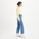 Person wearing a light yellow sweater and blue jeans on a white background
