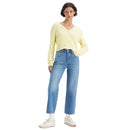 Woman wearing a yellow sweater and blue jeans on a white background