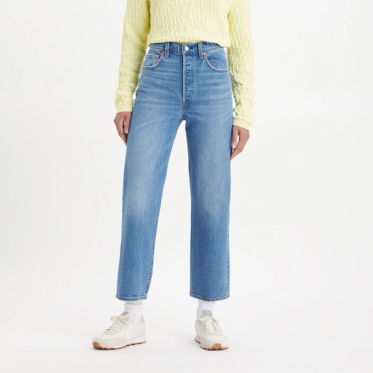 Person wearing light blue jeans and a yellow sweater on a white background