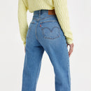 Person wearing blue jeans and a yellow sweater on a white background