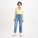 Woman wearing a yellow sweater and blue jeans on a white background