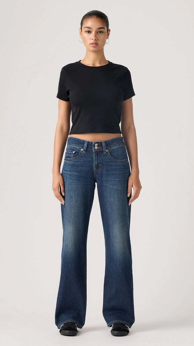 Person wearing blue jeans and a black top on a white background
