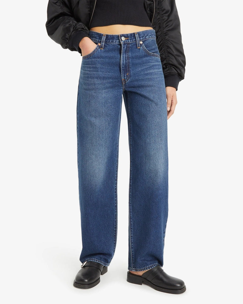 Person wearing blue jeans and a black top on a white background