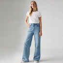 Woman wearing a white t-shirt and light blue jeans on a gray background