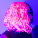 Person with glowing pink hair against a purple background