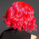 Person with vibrant red hair styled in waves against a dark background