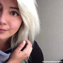 Person with white hair touching their hair against a plain background