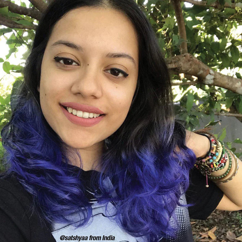 Woman with blue hair and colorful bracelets smiling outdoors