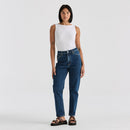 Woman wearing blue jeans and a white top on a plain background