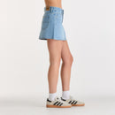 Person wearing a light blue denim skirt on a white background