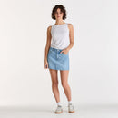 Woman wearing a white sleeveless top and light blue denim skirt on a white background