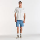 Man wearing a white t-shirt and blue denim shorts on a white background