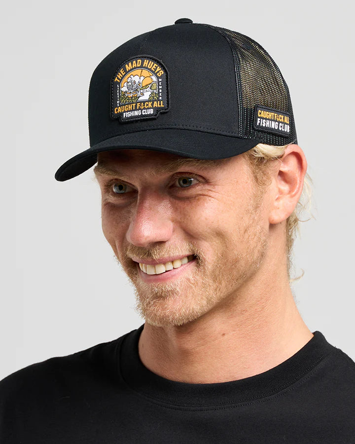 Man wearing a black cap with branding on a gray background