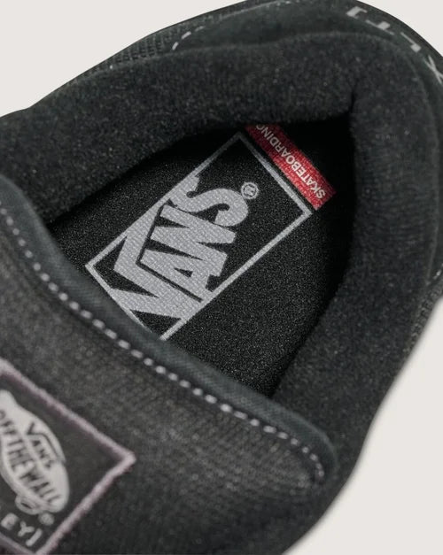 Close-up of a black sneaker with Vans branding on a light gray background