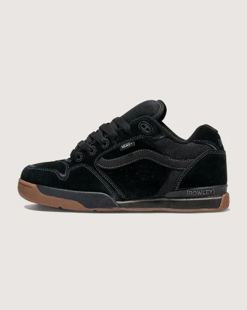 Black sneaker with brown sole on a light gray background
