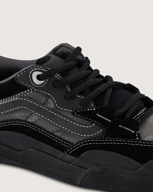 Close-up of a black sneaker with white stitching on a light gray background