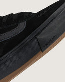 Close-up of a black sneaker with a brown sole on a light gray background