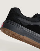 Black sneaker with brown sole on a light gray background