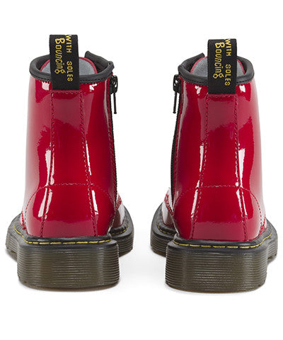 A red patent leather youth boot with a lace-up closure and a brand tag attached to it.