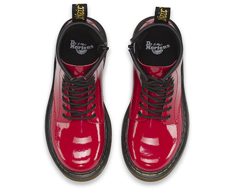 A red patent leather youth boot with a lace-up closure and a brand tag attached to it.
