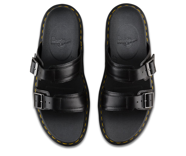 A pair of black Dr Martens Myles slide sandals with adjustable buckle straps and yellow welt stitching.