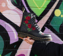 Person holding a Dr Martens 1460 Vonda Boot with a graffiti wall in the background 