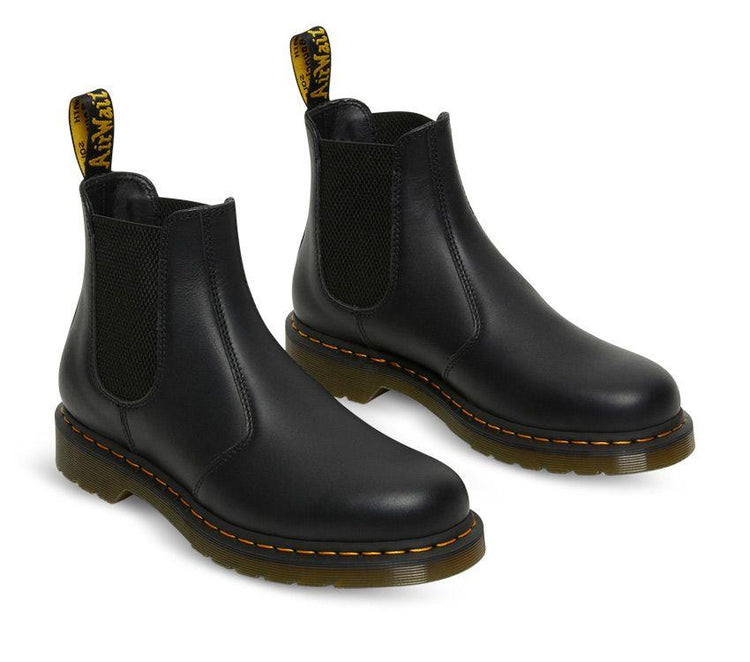 A pair of Dr Martens 2976 Black Nappa Leather Chelsea Boots with yellow welt stitching and the brand's logo visible.