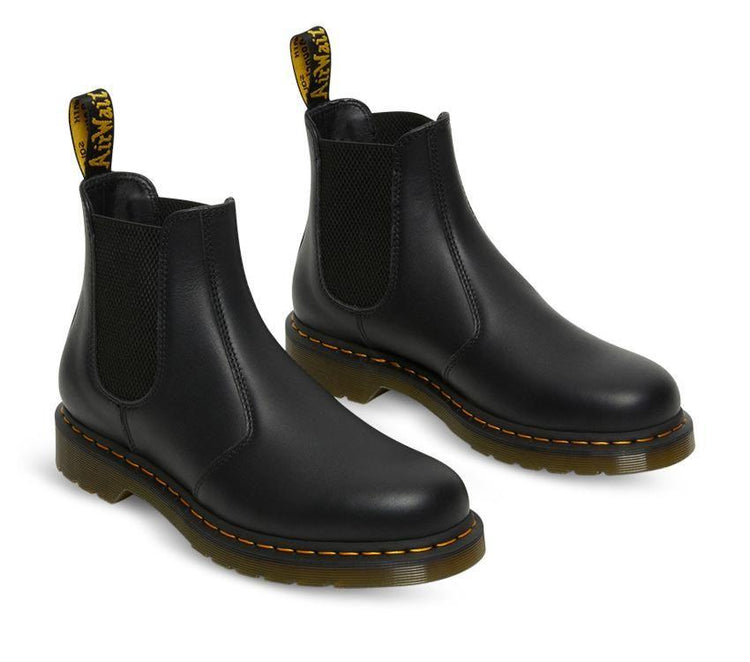 A pair of Dr Martens 2976 Black Nappa Leather Chelsea Boots with yellow welt stitching and the brand's logo visible.