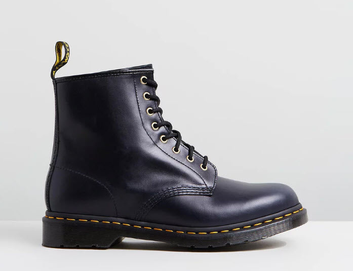 A navy-colored Dr Martens 1460 DM's boot with yellow stitching on the sole and a yellow metal eyelet.