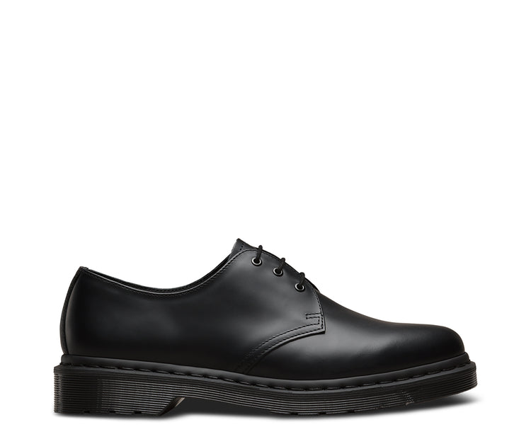 A monochrome black Dr Martens 1461 smooth leather shoe with a lace-up closure, visible stitching, and a flat sole.