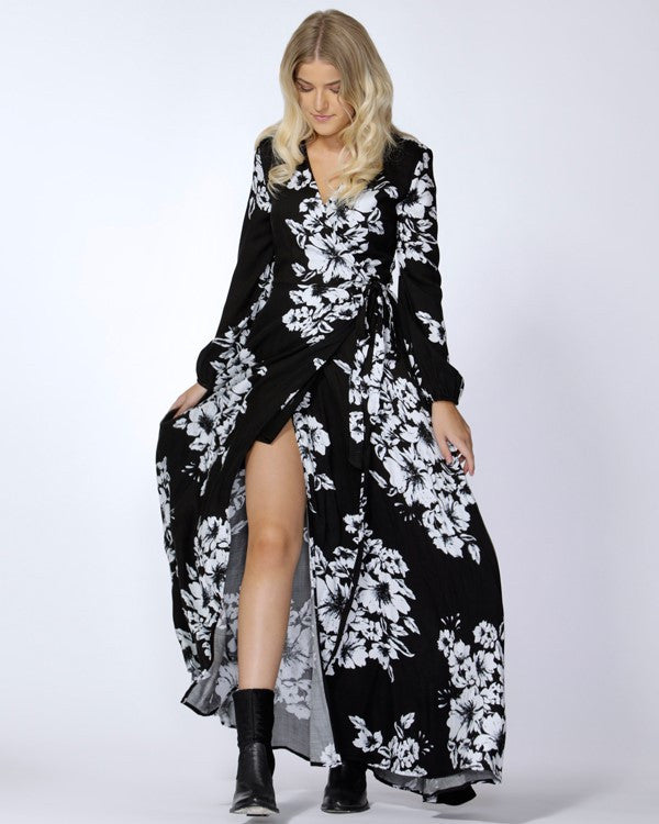 A model wearing a black and white floral wrap maxi dress with long sleeves and a V-neckline.