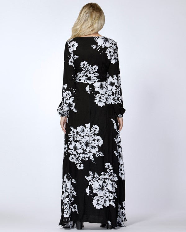 A model wearing a black and white floral wrap maxi dress with long sleeves and a V-neckline.