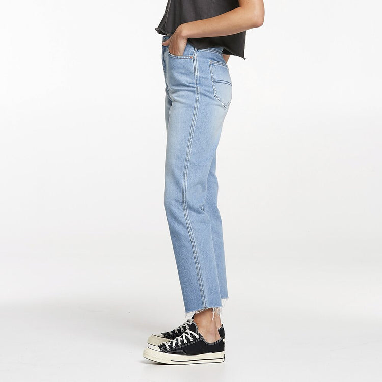 A person wearing high-waisted straight leg blue jeans and black sneakers.