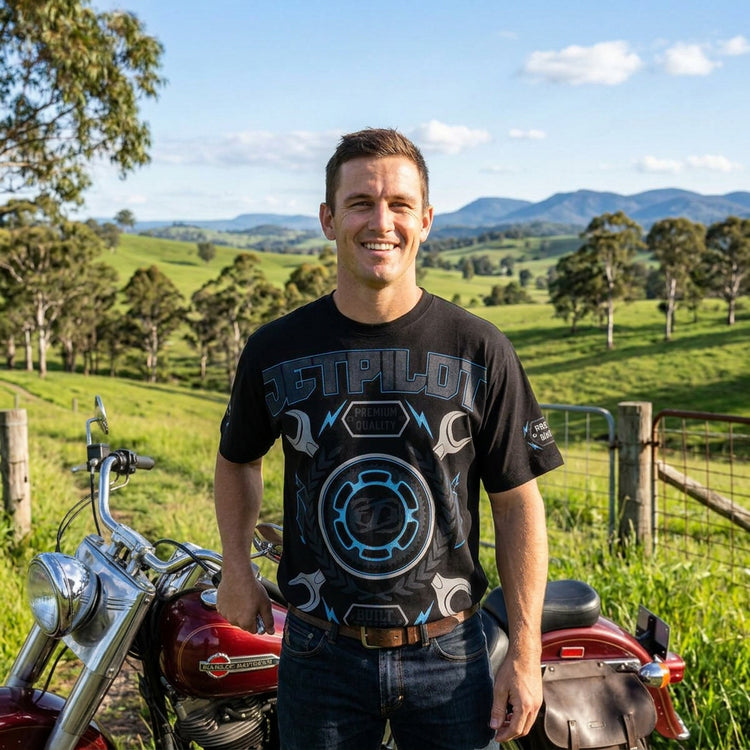 A man wearing a black Jetpilot branded t-shirt with a geometric pattern and text graphics.