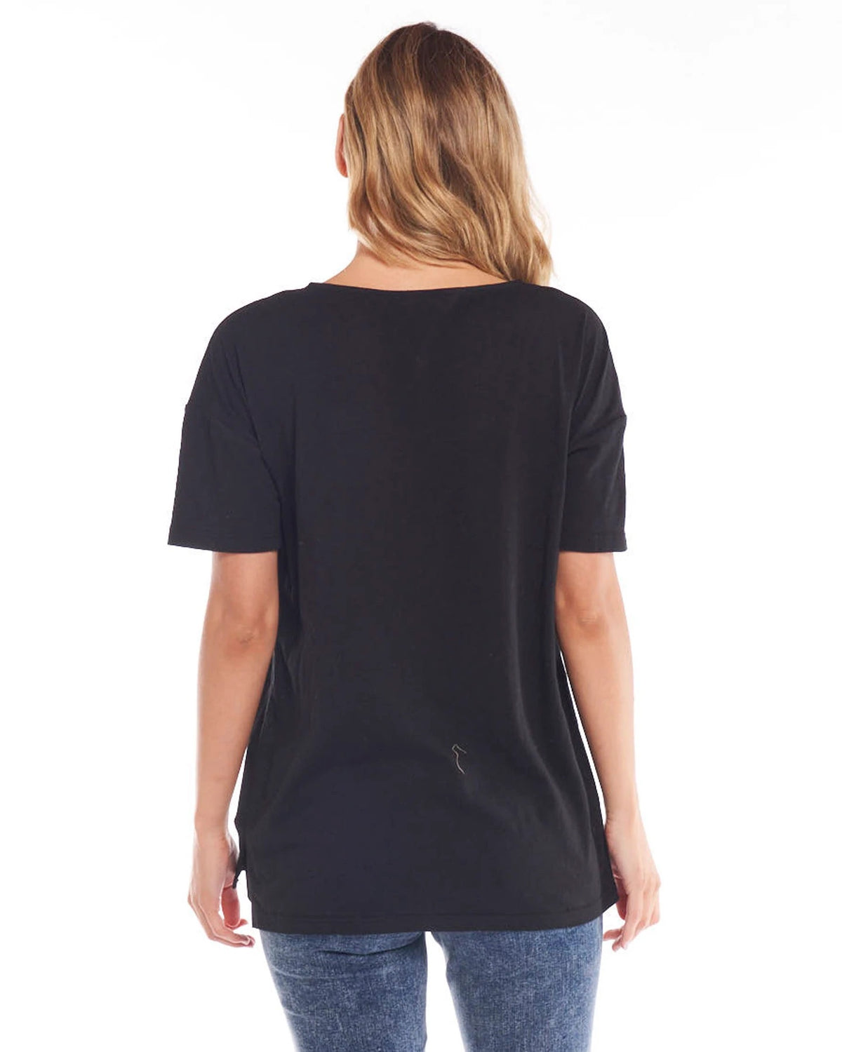 A female model wearing a black, Betty Basics relaxed fit t-shirt with a round neckline, short sleeves, and a side split detail.