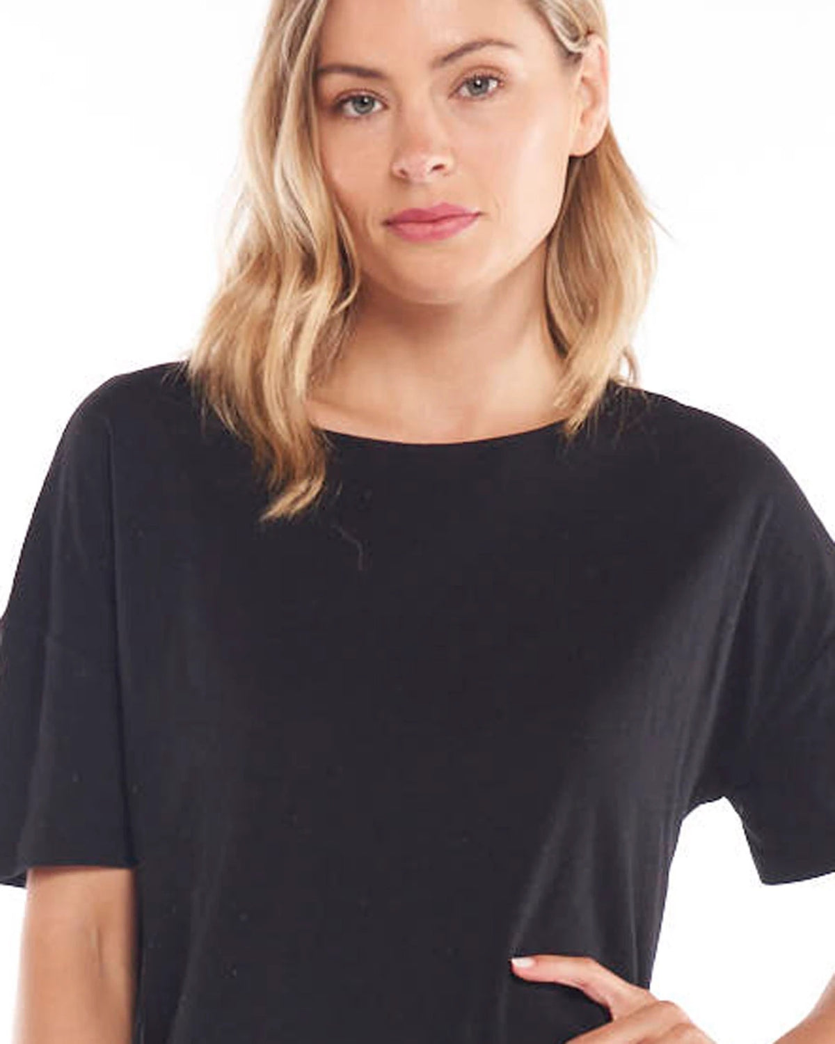 A female model wearing a black, Betty Basics relaxed fit t-shirt with a round neckline, short sleeves, and a side split detail.